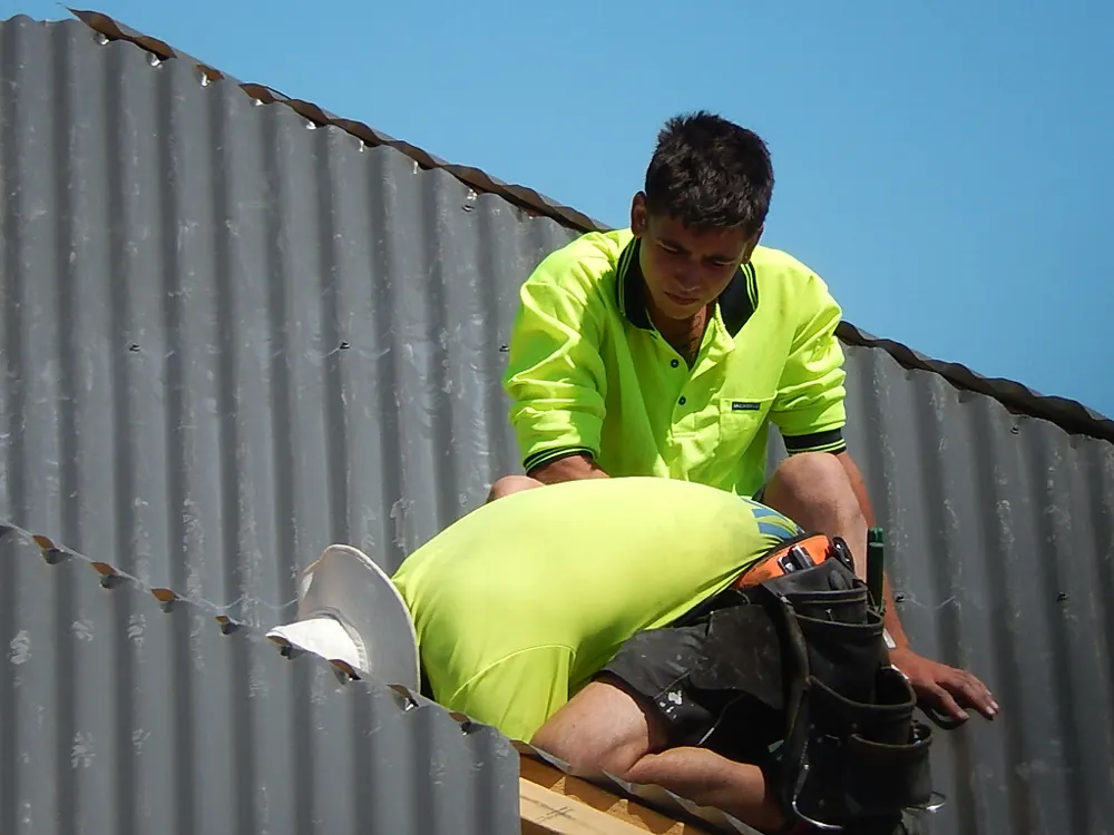 Roofer fixing new corrugated sheeting onto a roof